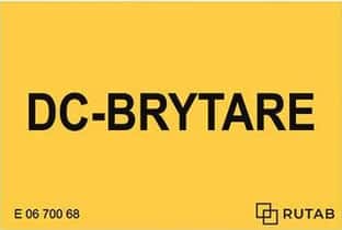 **Alt-text:** Bilden visar en gul skylt med svart text som lyder ”DC-brytare”. Skylten markerar en brytare för likström i en solcellsanläggning. Den används för att tydligt visa var frånkoppling av likström sker. Skylten bidrar till säker hantering och underhåll av anläggningen.
